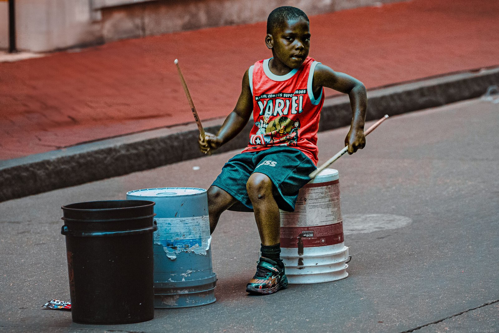 Young boy playing drums on the street, candid portrait photography