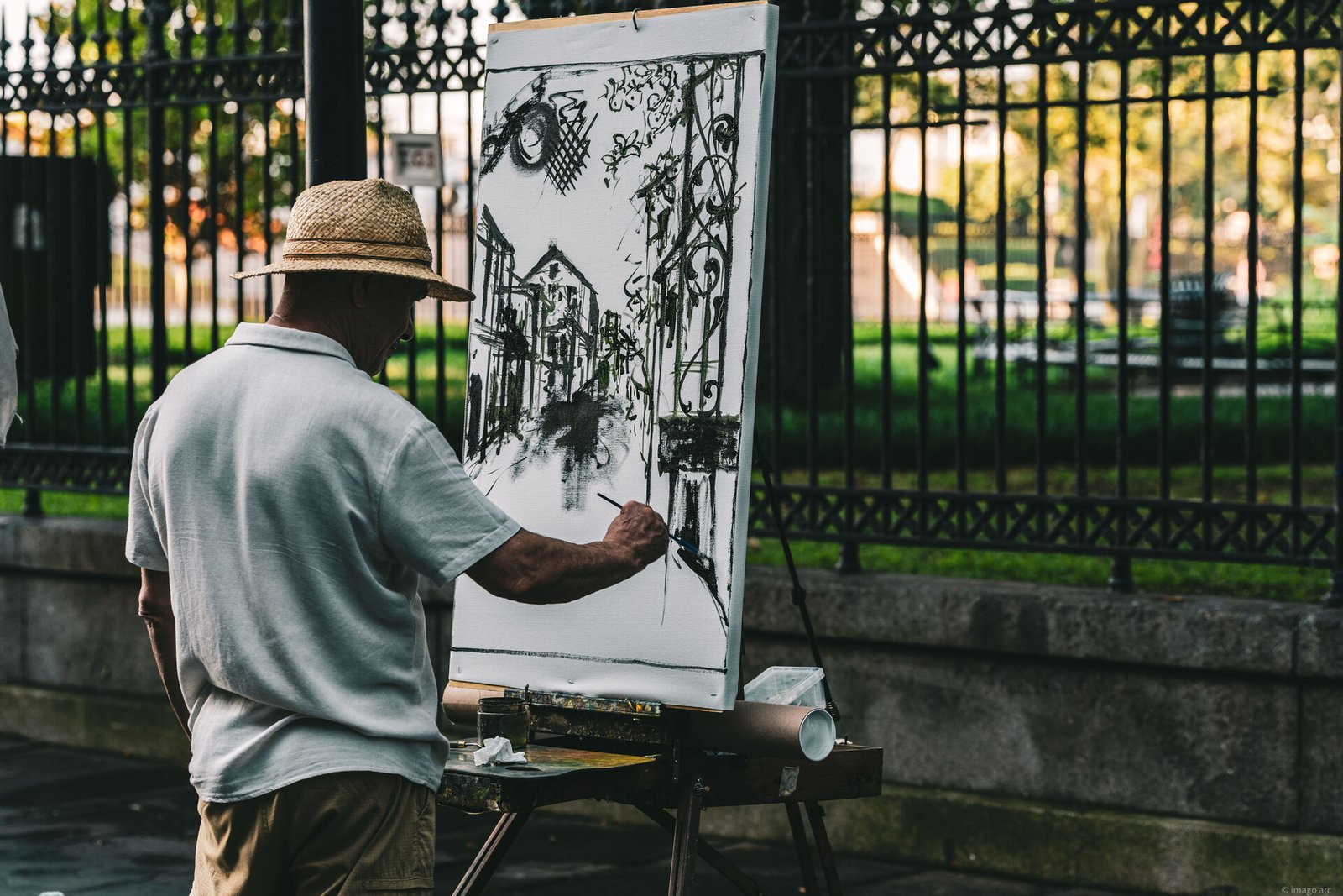 Street artist creating work on a city sidewalk, documentary photography