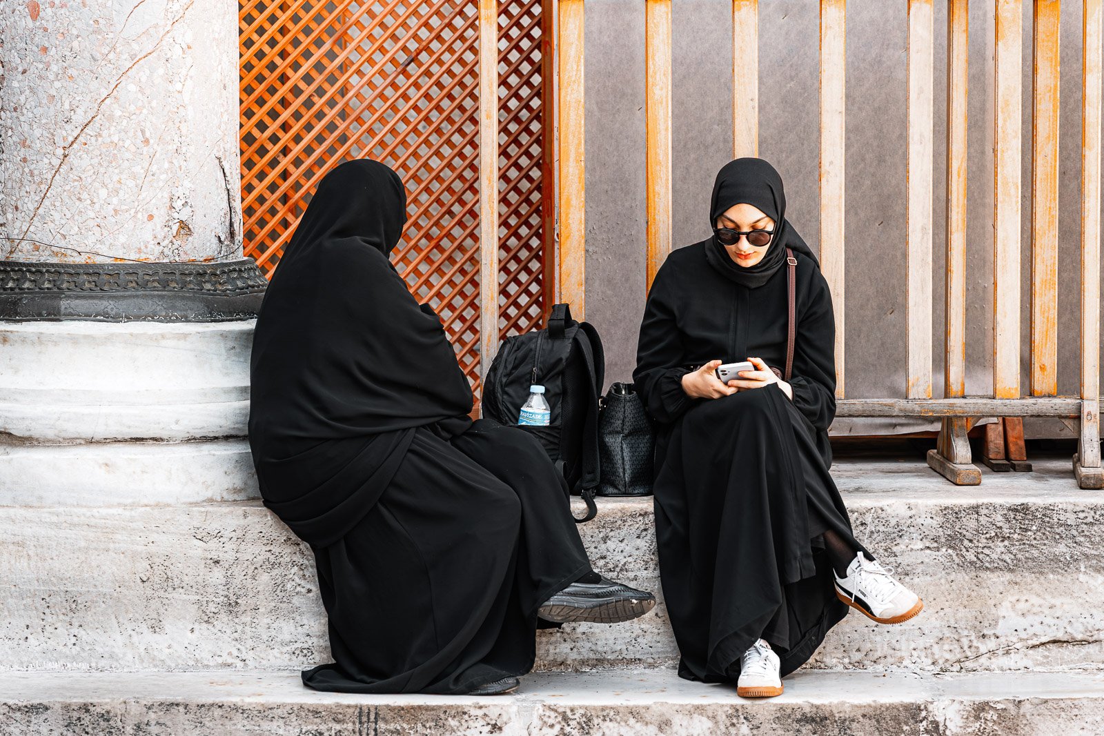 Women sitting on stone steps in afternoon light, street photography