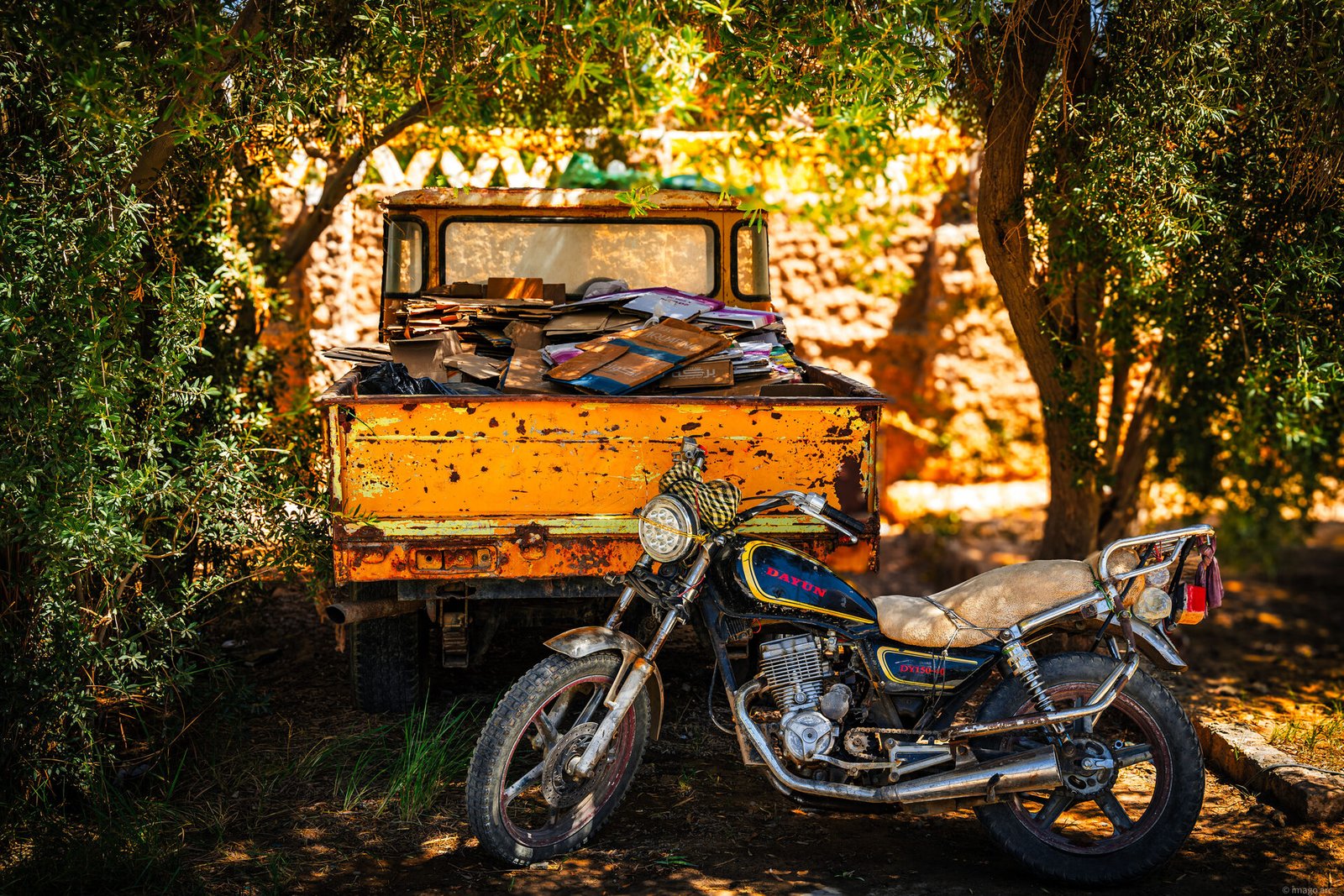 Motorcycle parked beside a weathered truck on a dusty road, travel photography
