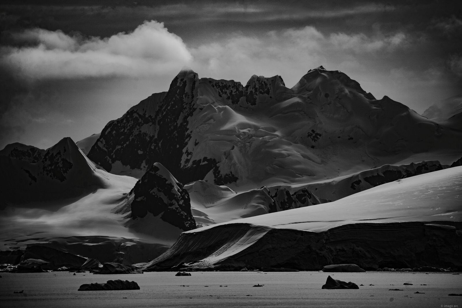 Snow-covered mountain range rising above icy waters in Antarctica